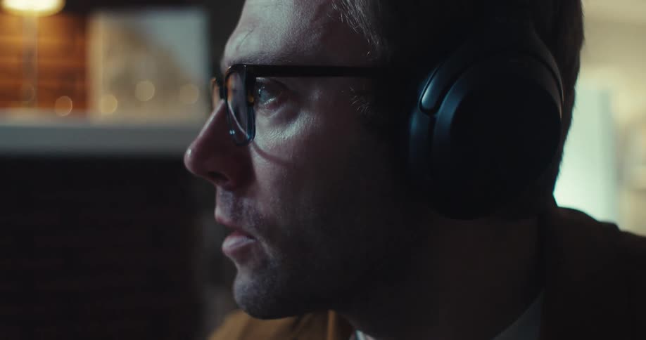 A man wearing headphones nods his head as he talks quickly