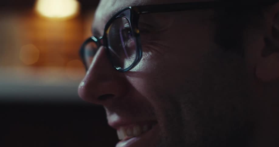 A man in a room excitedly looking at a binary options chart on the computer