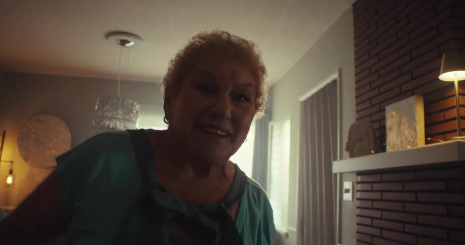 An older woman happily dancing in her living room