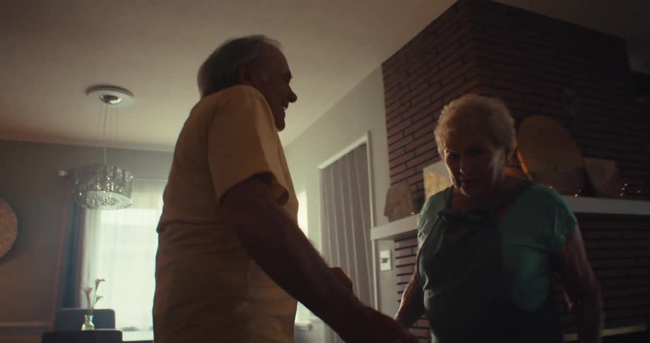 Happy elderly couple dancing in their living room having a great time
