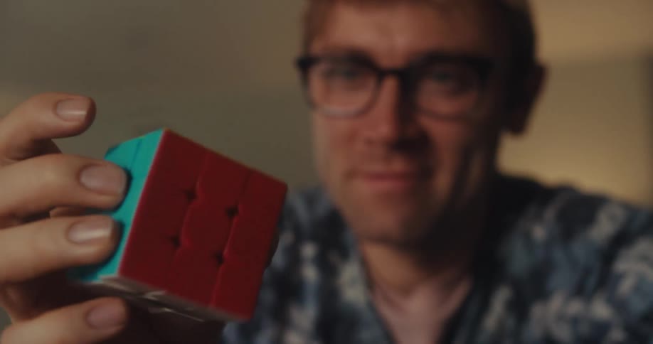 A man holding and twisting a rubiks cube with one hand
