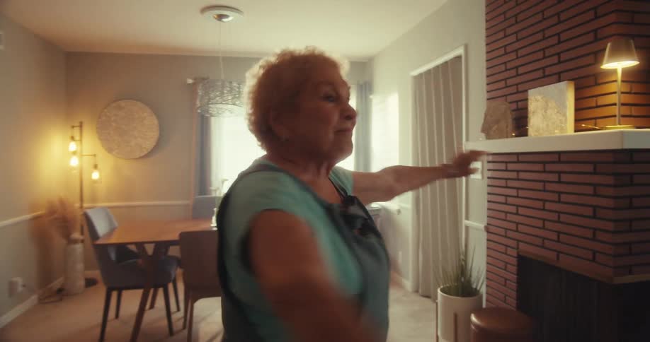 Elderly woman dancing inside the house during the day