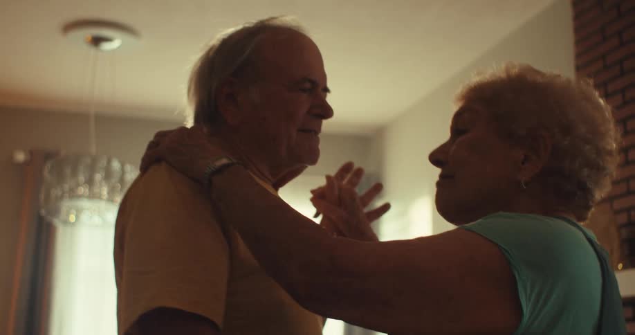 A couple are smiling and dancing together