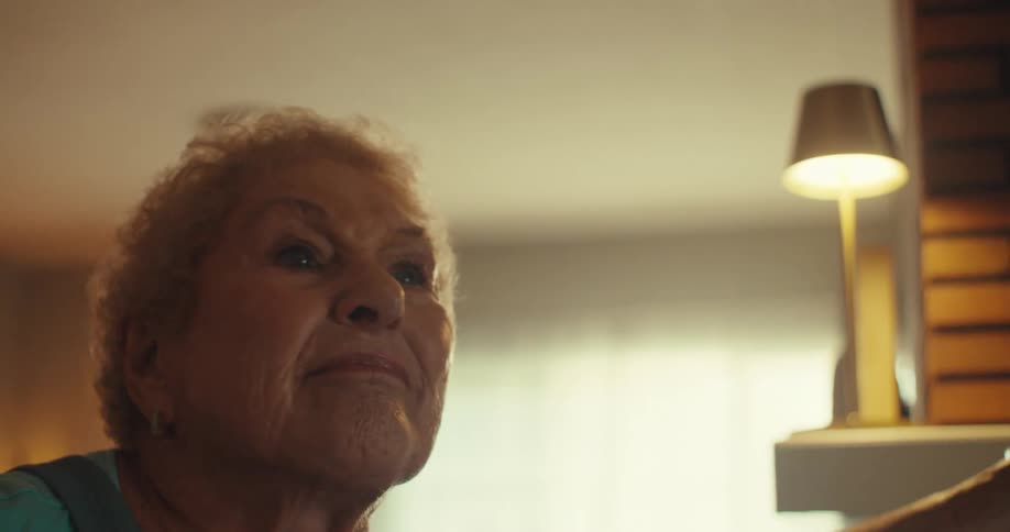 An elderly couple dances joyfully indoors with big smiles on their faces