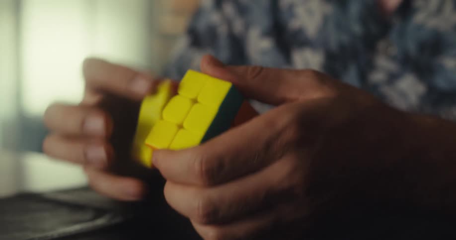 Closeup of a mans hands skillfully solving a rubiks cube and finishing triumphantly