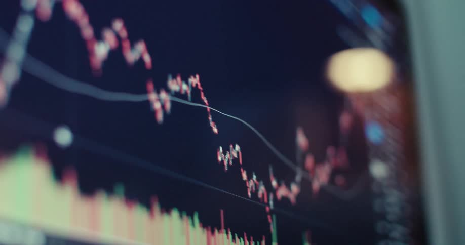 A closeup shot of a screen displaying fluctuating stock market graphs and numerical data