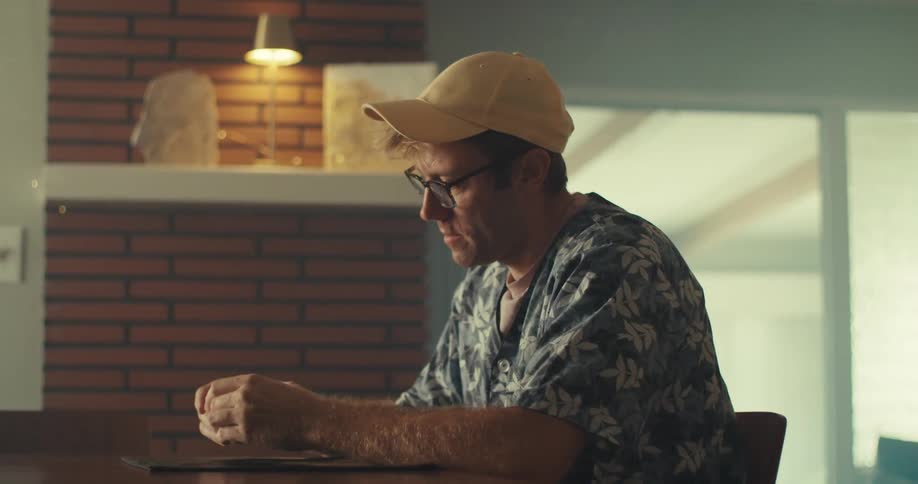 A determined man sits in a chair focused on solving a rubiks cube puzzle