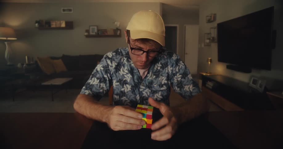Man solves a rubiks cube on a table top in a living room