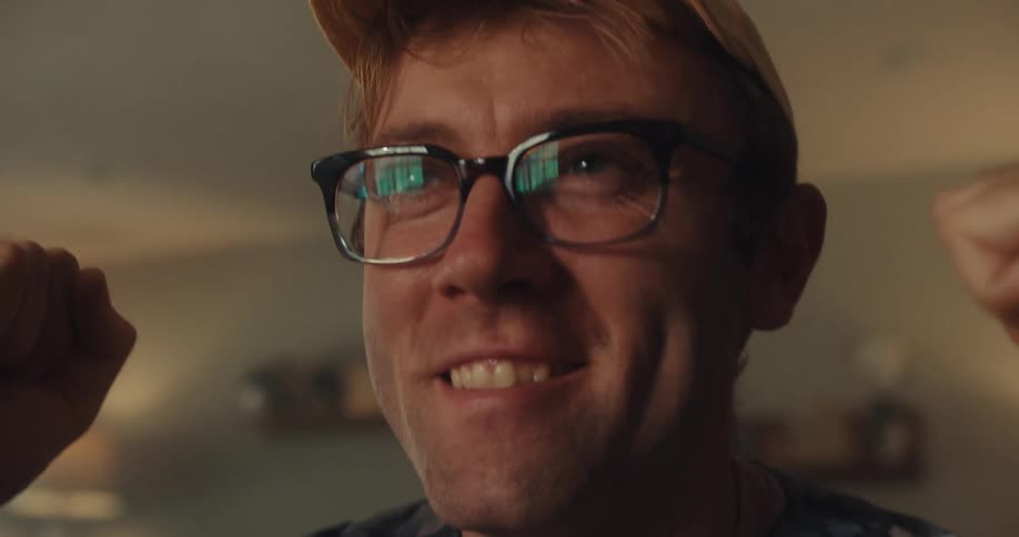 A man at a table in the living room solving a rubiks cube and celebrating