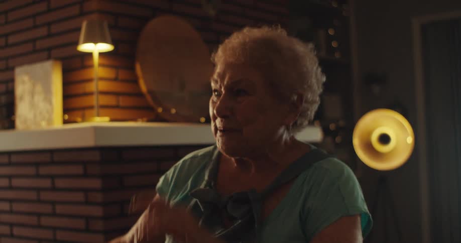 An elderly couple dancing and smiling in the living room of a house