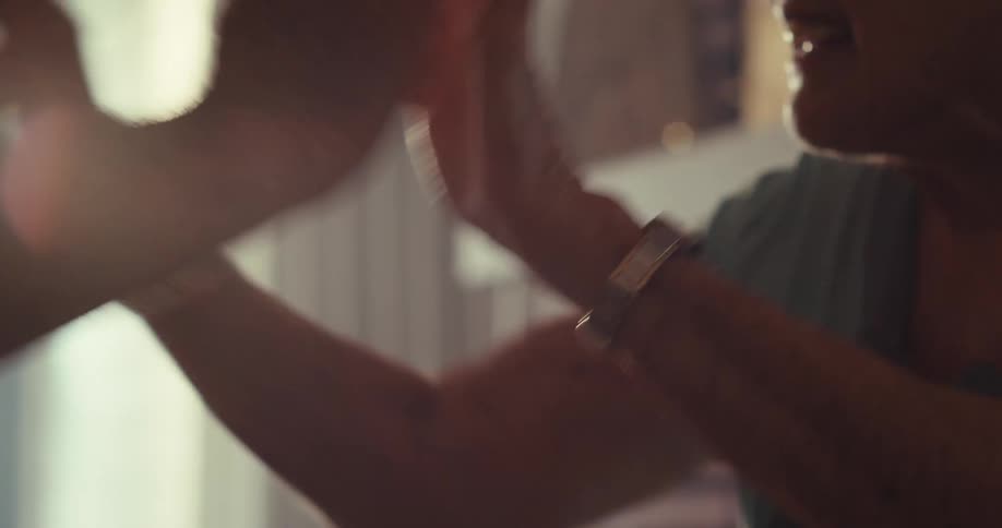 An elderly couple dance and play around slapping their hands together in a living room