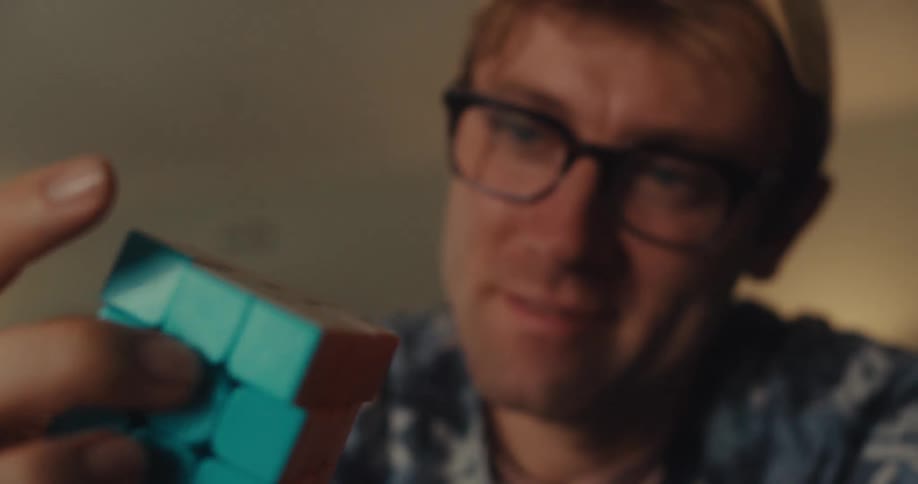 A man holding and twisting a rubiks cube in his hand
