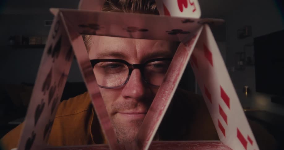 Man nods and smiles while admiring an arrangement of cards on a table in a living room
