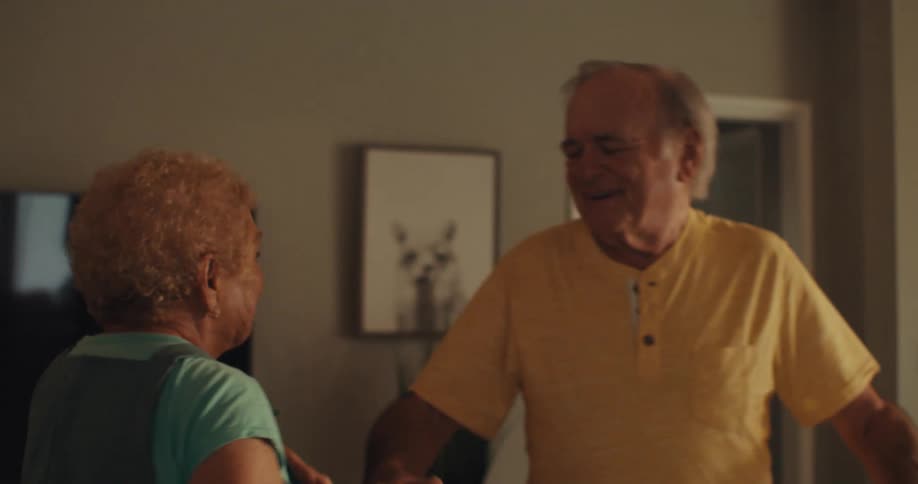 An elderly couple dancing in their living room at home