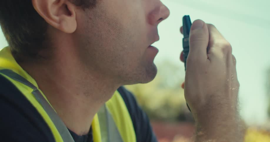 A man turns to talk into the walkie talkie