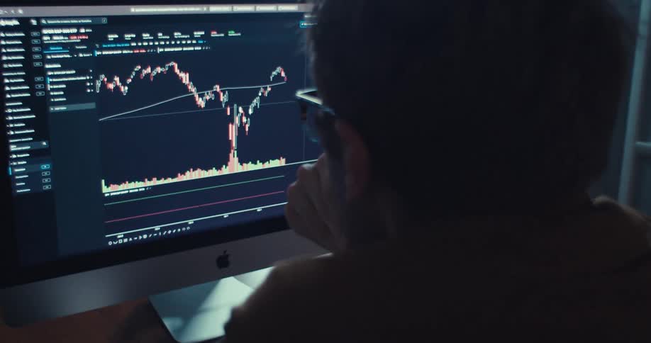 Man puts on his eyeglasses and concentrates on a plot displayed on his computer