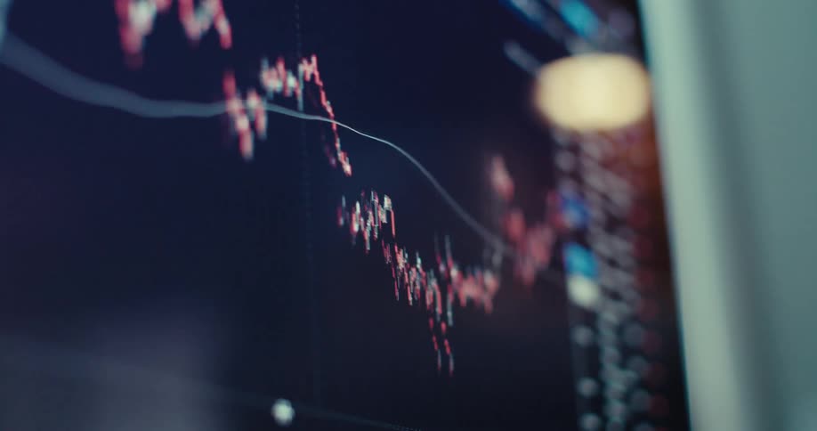 A stock market screen displays a sharp decline in a candlestick chart alongside a list of trading data