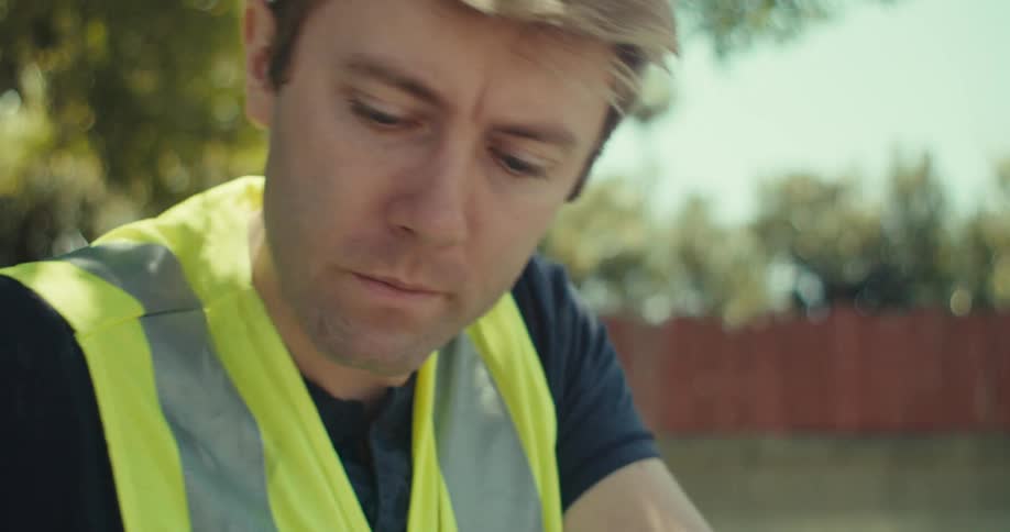 The worker writes on a post it on the blue prints