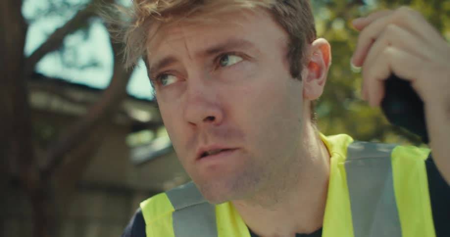 A man talks into a walkie talkie in the yard