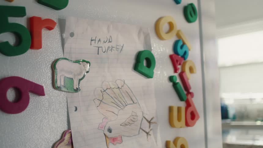 Magnets and a drawing of a turkey are on the fridge
