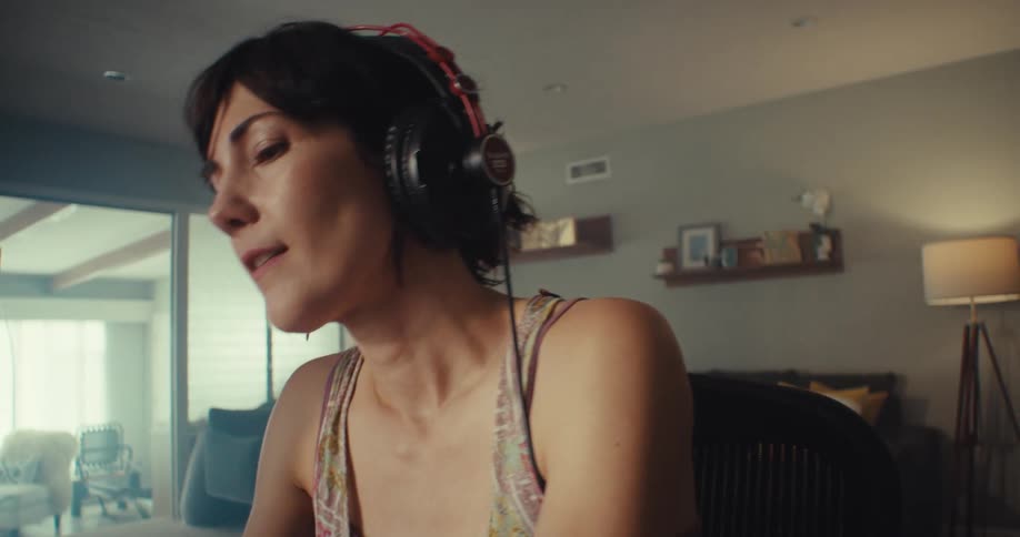 A woman is dancing in her seat as she listens to music on her headphones