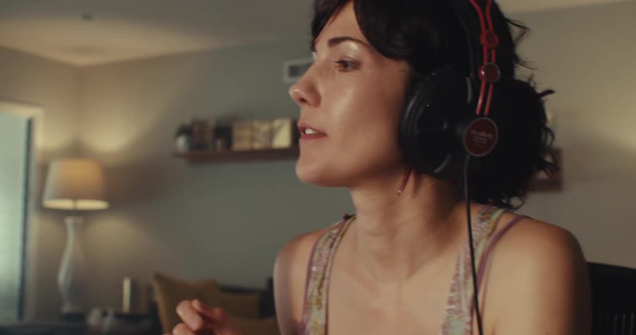 A woman wearing a headset dances and grooves to music while relaxing and enjoying herself