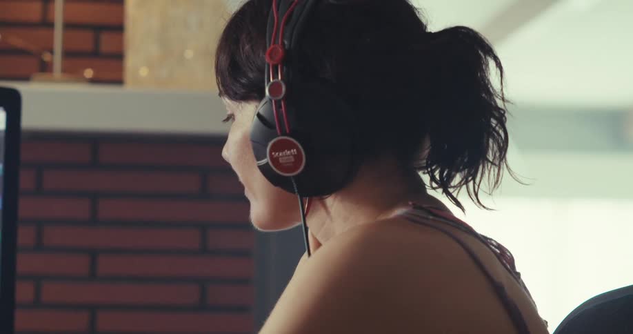 A woman is using a soundboard and looking at a monitor