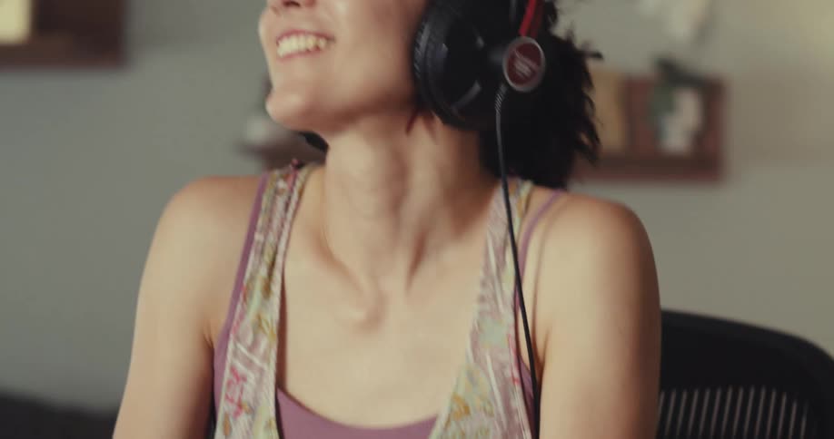 A woman is dancing in her chair while listening to music that she is creating with a midi controller