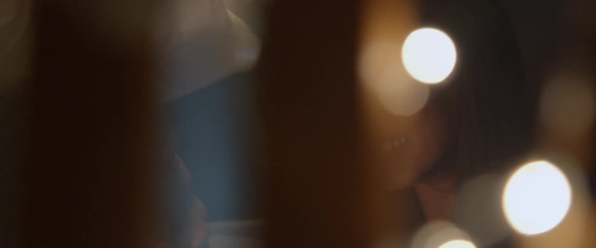 Child kisses mom on cheek while surrounded by white lights