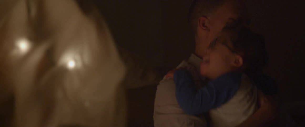 Man holding a young boy that is wearing glasses in a dark setting