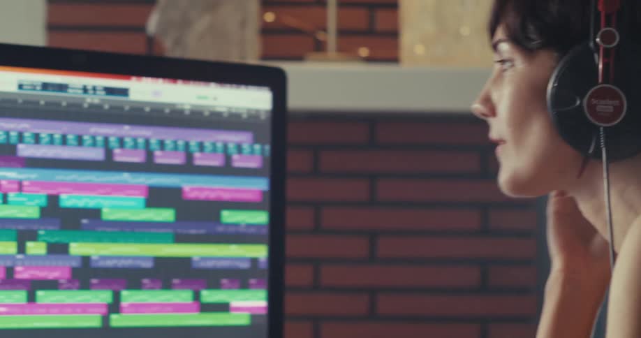 Person with headphones focused on a colorful audio workstation screen indoors