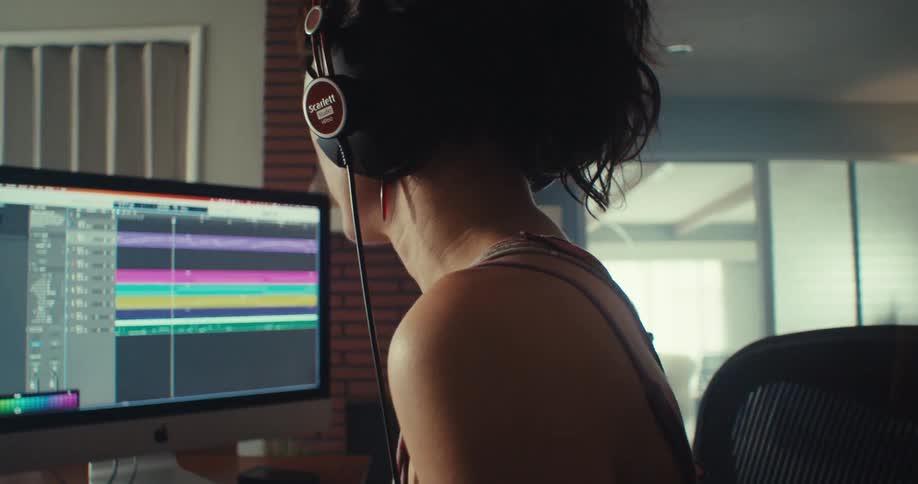 Close up of a woman mixing beats on a desktop computer in a room