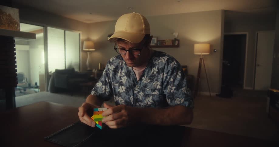 Man solving a rubiks cube in his living room then relieved and happy when he succeeds