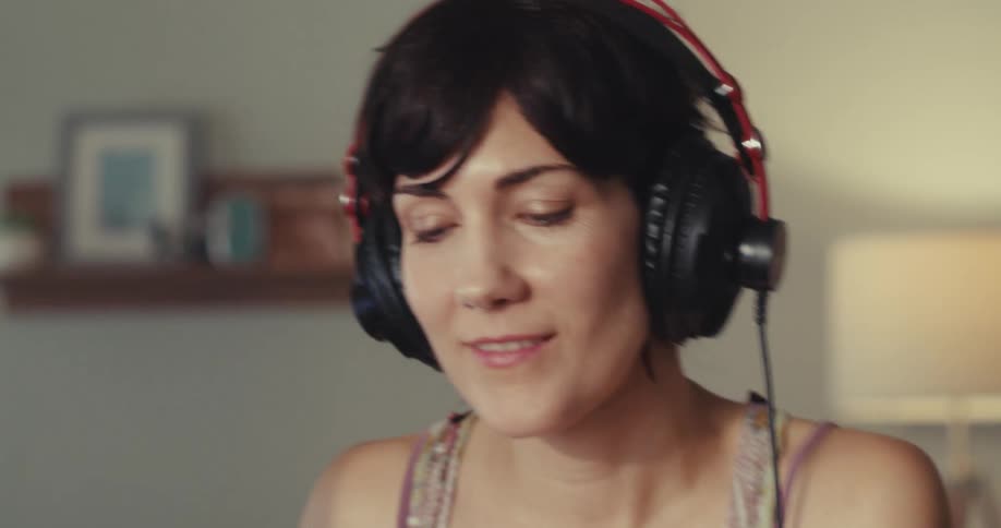 A woman is listening to music and using a soundboard with headphones
