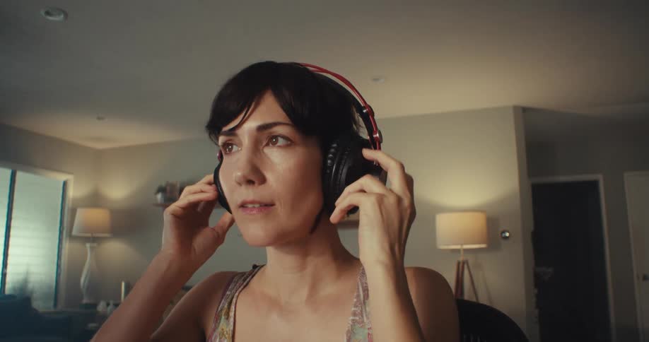 A woman putting on headphones to listen to something and smiling