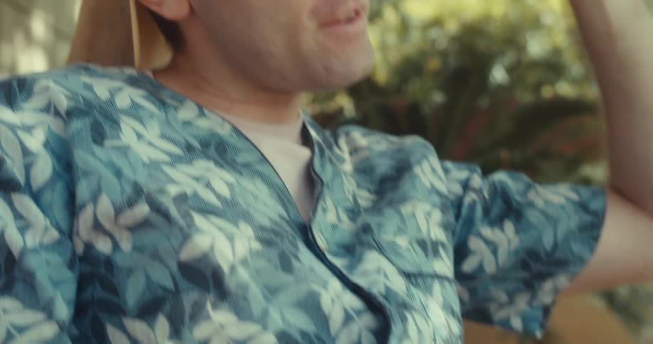 A man sits in a nature park happily singing while looking at his smartphone