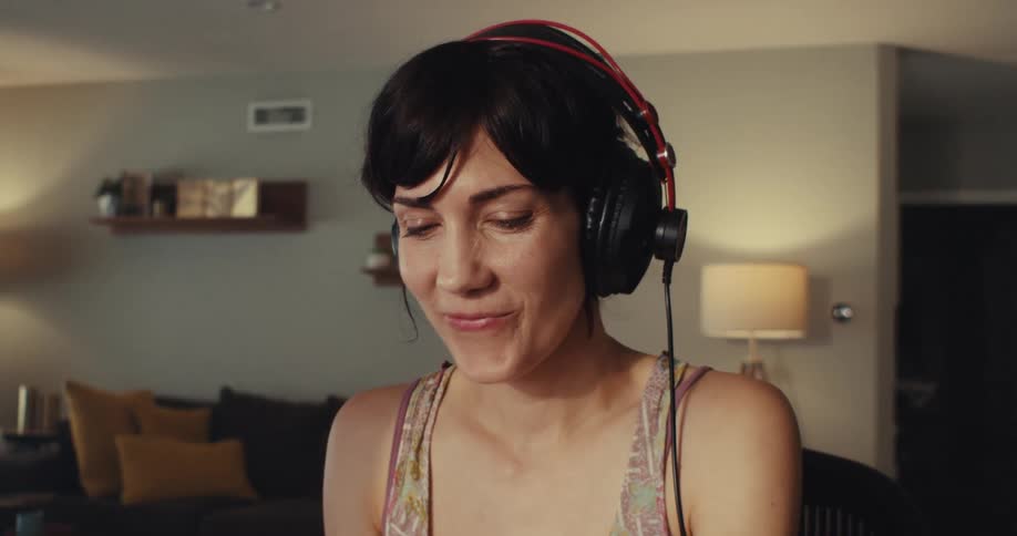 A woman is smiling while listening to music on headphones