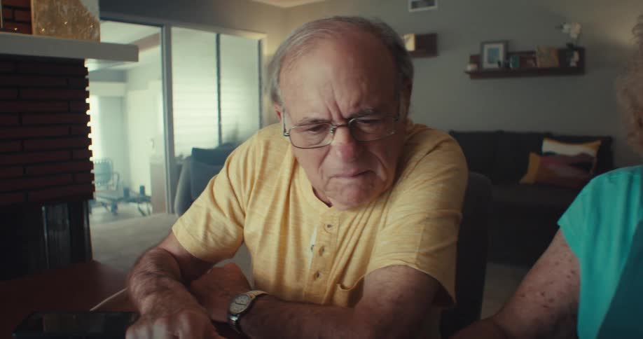 A man uses a laptop as a woman looks over documents