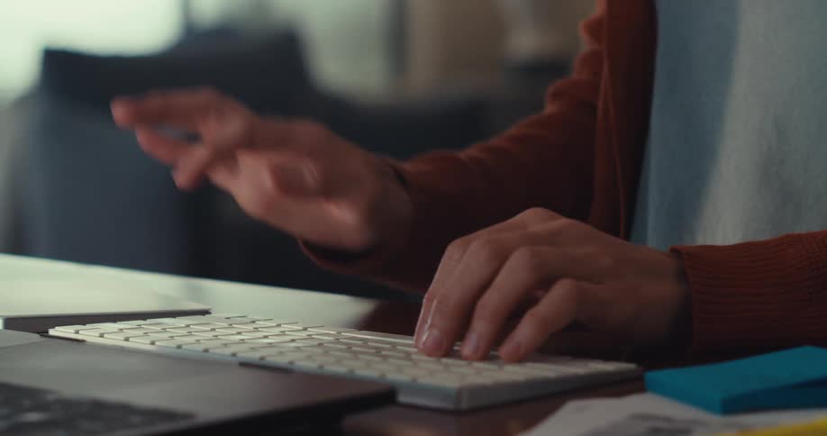 A woman sitting at a table typing on a keyboard and smiling happily