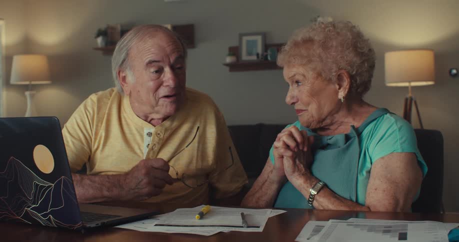 Elderly couple smiles warmly and shares a loving chat in the cozy living room