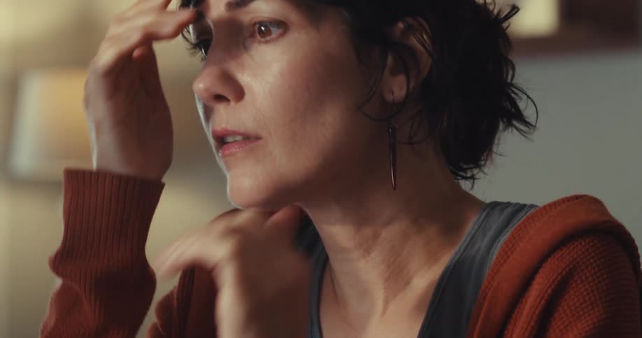 A woman in distress puts her hands on her face then looks at a computer monitor