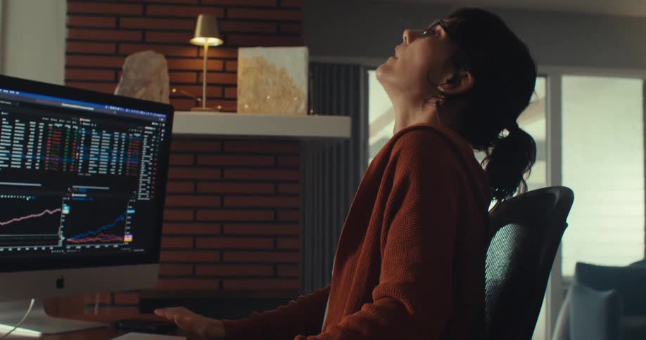 A woman sits at her computer and expresses frustration
