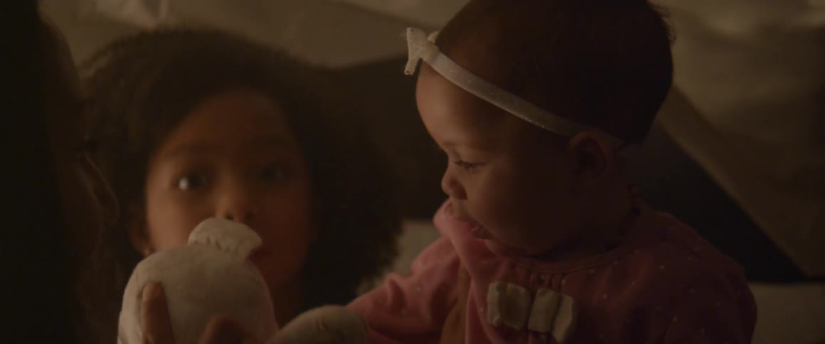 A woman plays with a teddy bear, a baby and a little girl