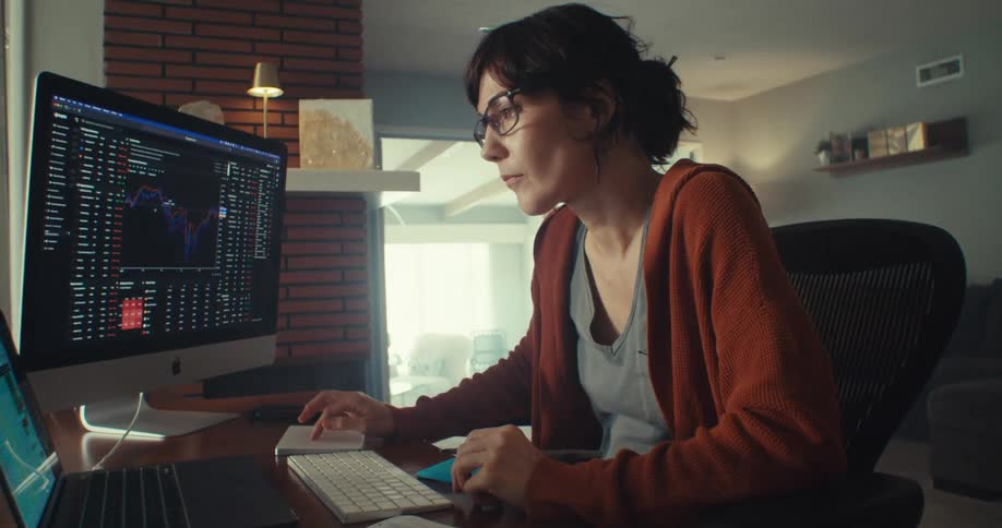 A woman looks at her computer and writes on a post it