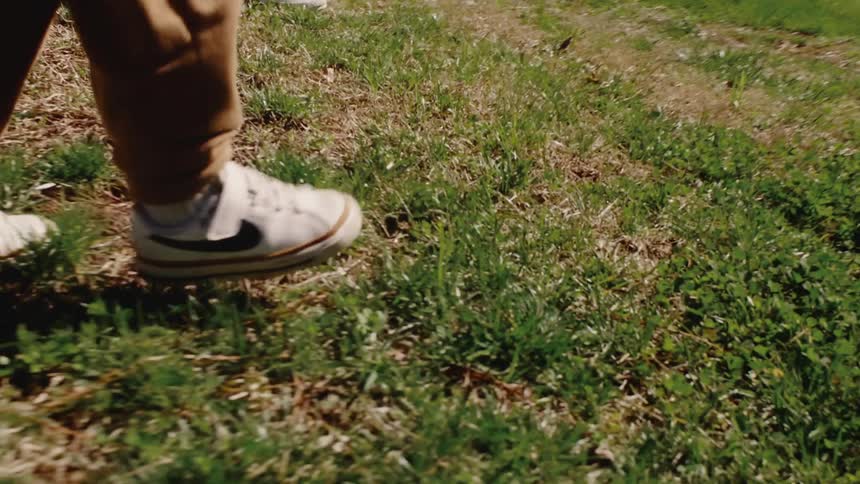 Two children in sneakers walk across a grassy backyard