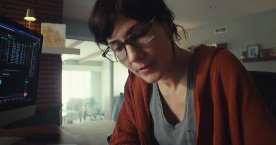 Woman sitting near a computer in her living room highlights elements of a document
