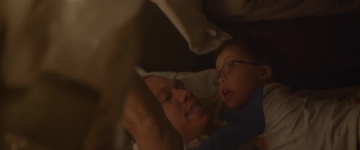 A man and baby lie on a bed before bedtime