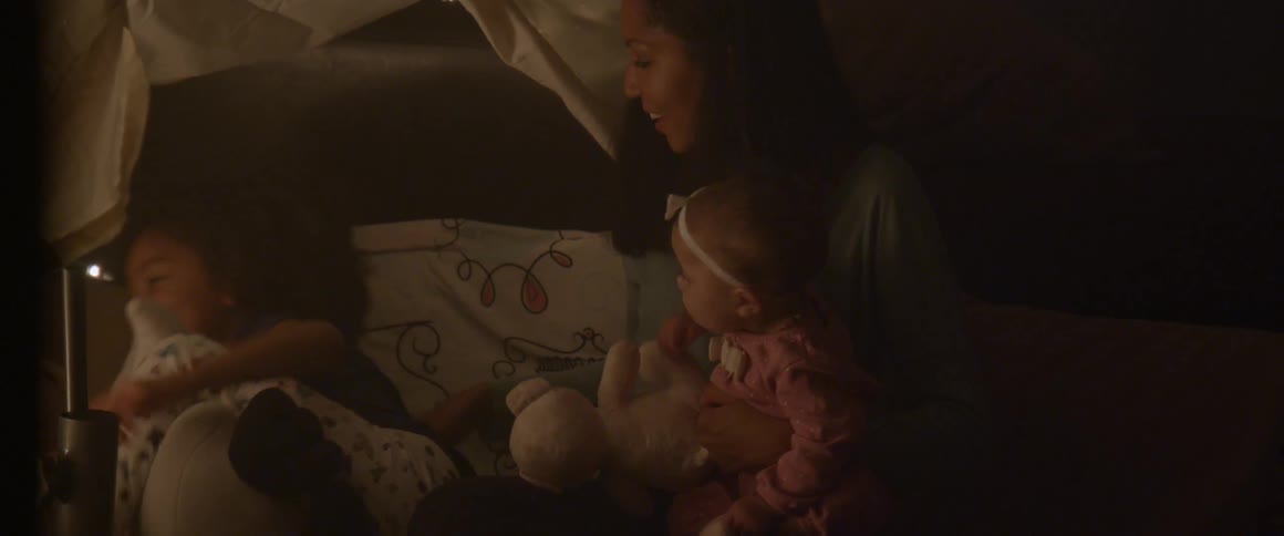 A woman sits with her children in bed