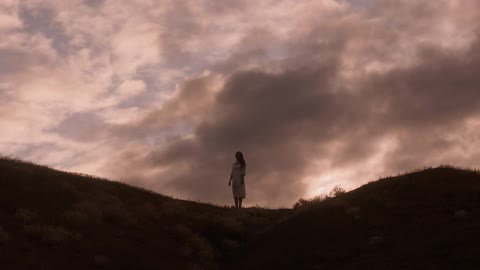 Woman standing on ridge of a hillside at sunrise