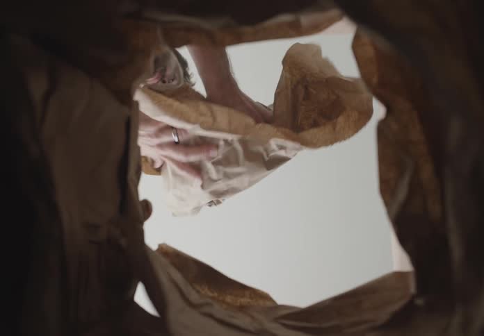 A man wraps a box with plastic wrap and places it inside a bag